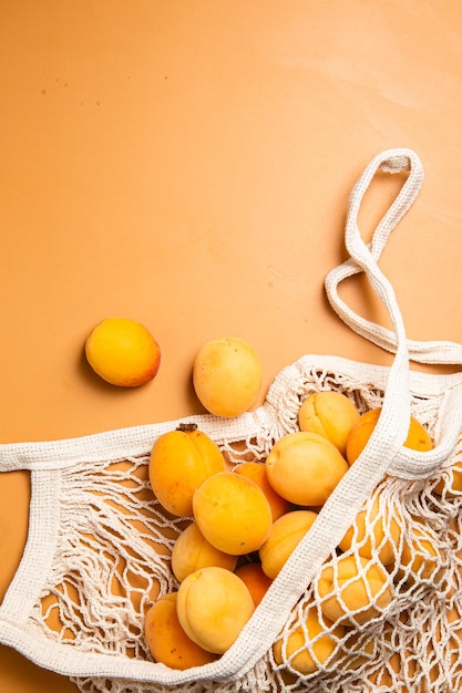 Apricots in an eco bag on a bright background Purchase