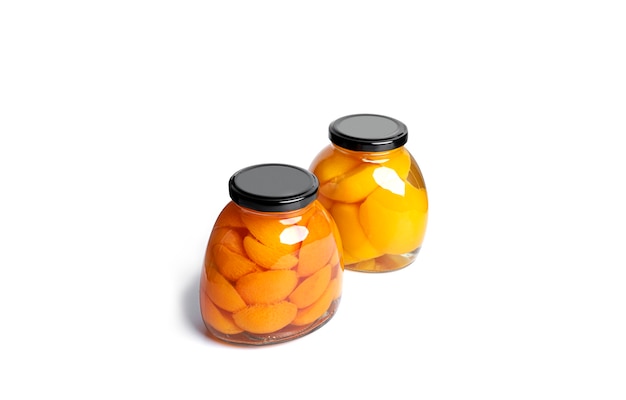 Apricots and peaches canned in glass jar. Sweet apricots and peaches in syrup isolated on white.