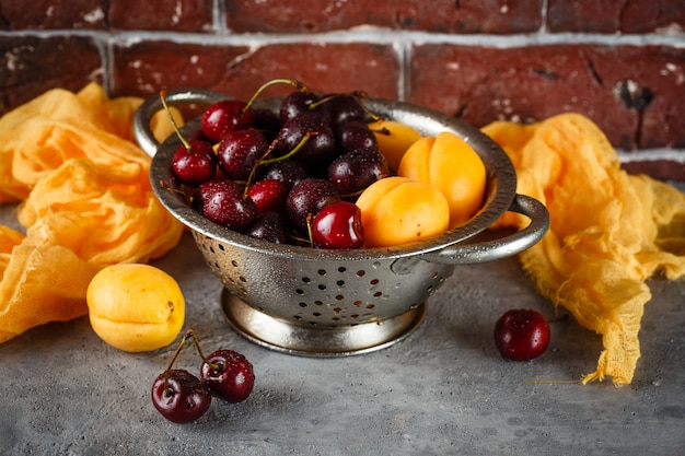 Apricots, sweets cherries in colander