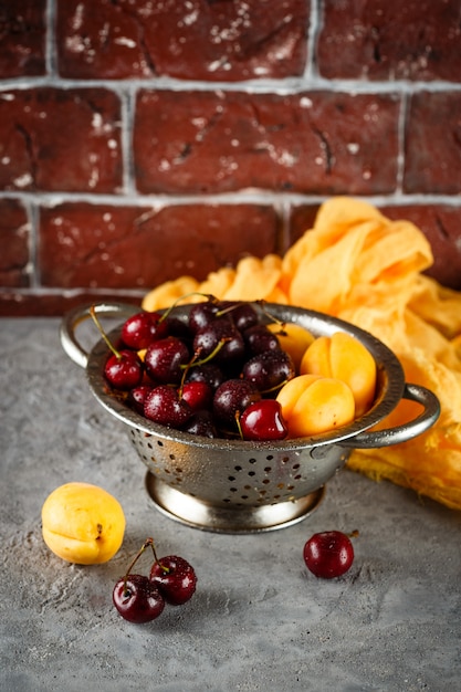 Apricots, sweets cherries in colander
