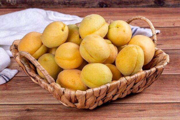 Apricots on wood background A pile of fresh apricots in a basket close up