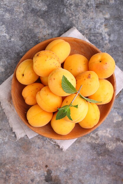 Apricots in a wooden plate with mint leaves