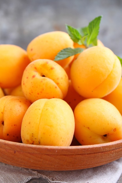 Apricots in a wooden plate with mint leaves