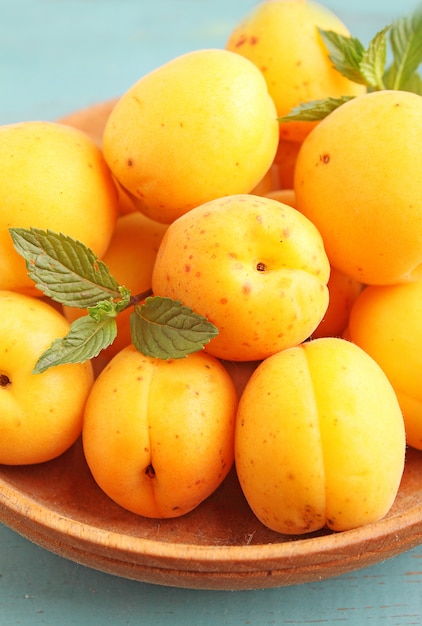 Apricots in a wooden plate with mint leaves