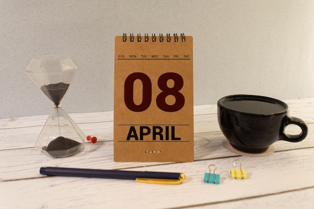 April 08 calendar date text on white wooden block with stationeries on wooden desk