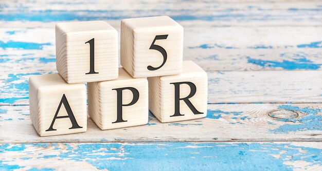 April 15th. Wooden cubes with date of 15 April  on old blue wooden background.