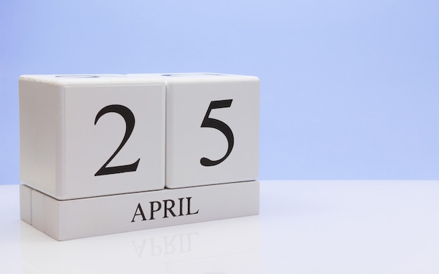 4月25日月の25日目、反射と白いテーブルに毎日のカレンダー