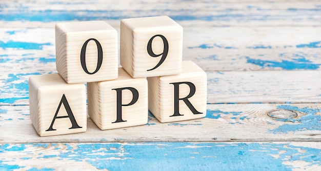 April 9th. Wooden cubes with date of 9 April  on old blue wooden background.