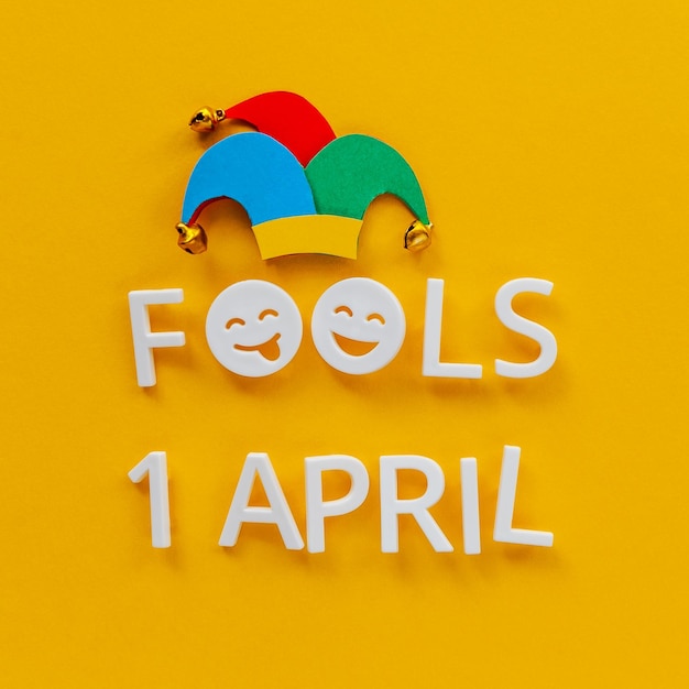 Photo april fools day over yellow background with jester hat first april card with laughing face