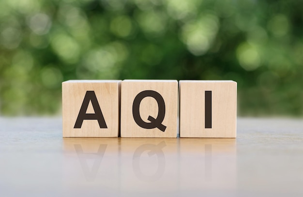 Aqi abbreviatie van luchtkwaliteitsindex woord geschreven op houten blokken de tekst is in zwarte letters geschreven en wordt weerspiegeld op het spiegeloppervlak van de tafel bedrijfsconcept voor uw ontwerp