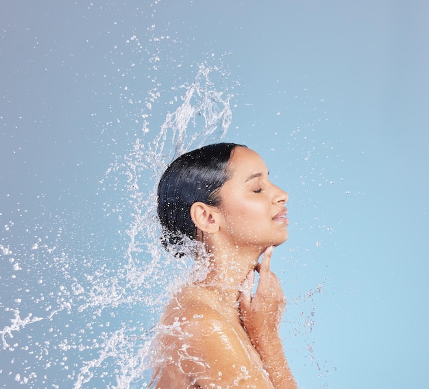 The aqua queen keeping it clean Studio shot of an attractive young woman taking a shower against a blue background