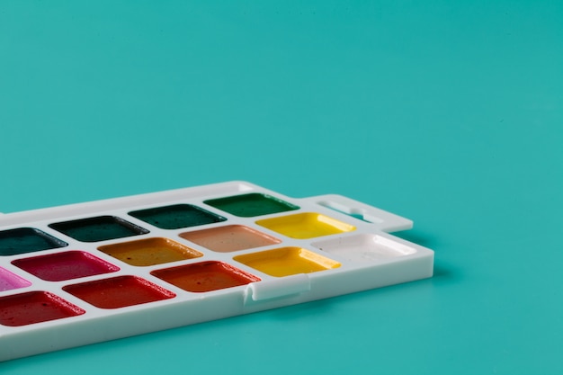 Foto aquarelle kleuren in een plastic doos op een aquamarijn achtergrond