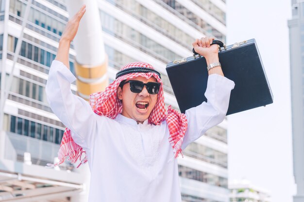 Arab businessman standing by raising both hands up in city