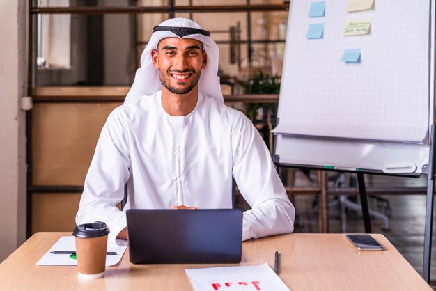 Arab businessman wearing traditional emirates kandura at work in a Dubai international company