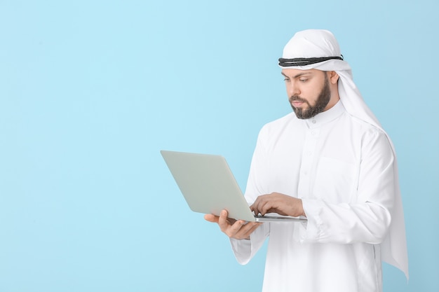 Arab businessman with laptop on color