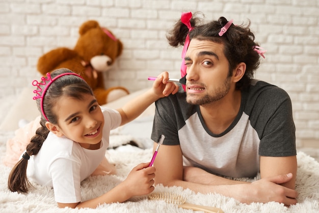 Arab Dad with Daughter are Laying on a Couch.