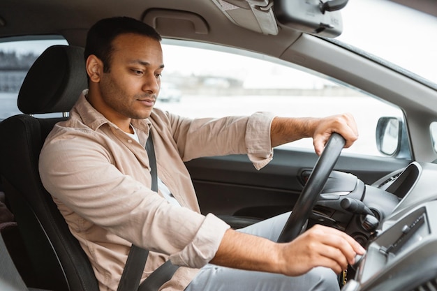 Photo arab driver guy driving automobile pushing buttons on dashboard pannel