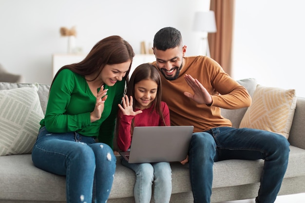 Famiglia araba che fa una videochiamata usando il portatile agitando le mani