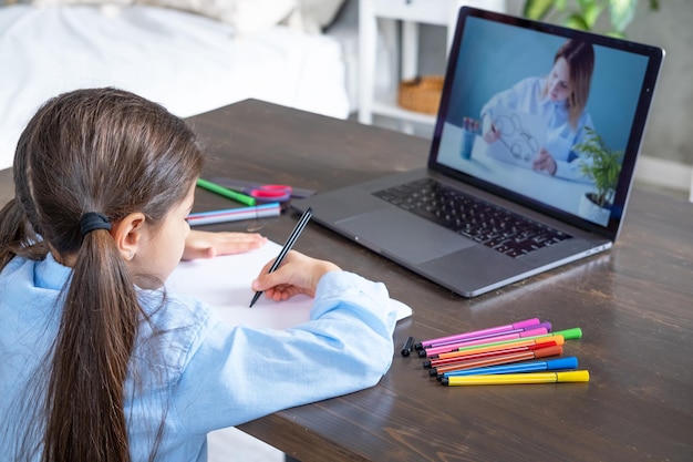 Arab girl having online lesson education using laptop kid\
learning to draw with teacher online