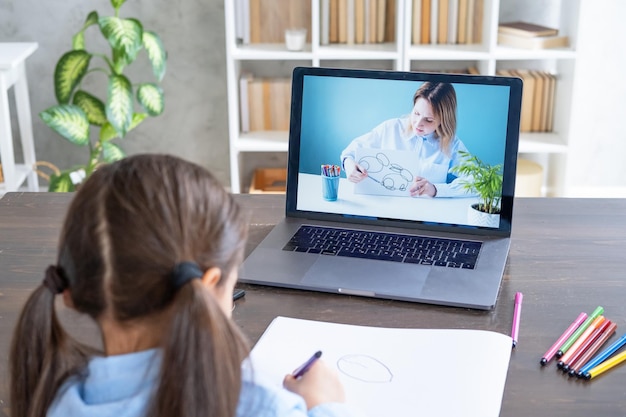 arab girl having online lesson education using laptop kid learning to draw with teacher online