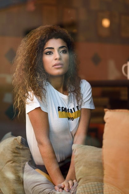 Arab girl sitting in a bar with worried face