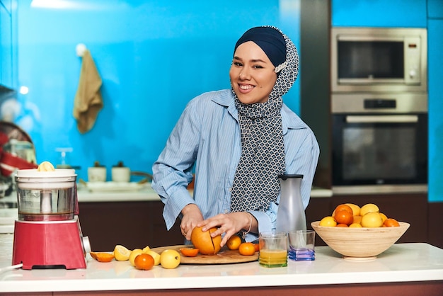 モダンなキッチンでフルーツジュースを作るアラブのヒジャーブの女性ホームコンセプト健康的なライフスタイルのコンセプトセレクティブフォーカス高品質の写真