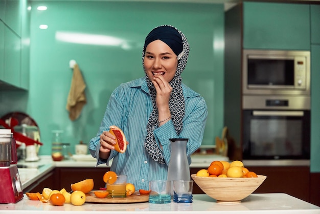 Arab hijab woman making fruit juice in modern kitchen Home concept Healthy lifestyle concept Selective focus High quality photo