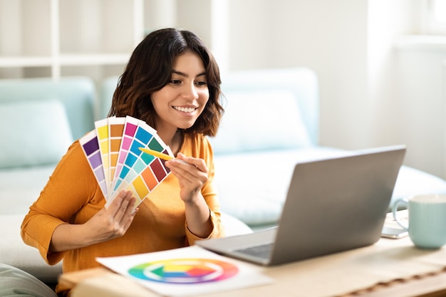 Arab Interior Designer Lady Showing Swatches To Client Via Teleconference On Laptop