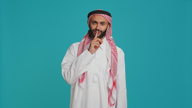 Photo arab man does silence sign with finger