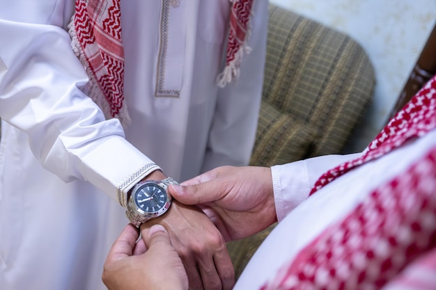 한 아랍 남자가 아랍 친구에게 손목시계를 선물합니다.