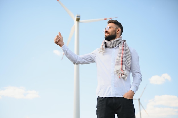 Arab man standing with wind turbine on mountain