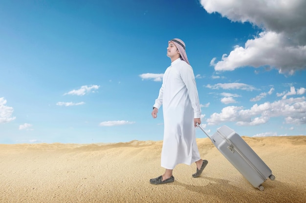 Arab man wearing keffiyeh and agal walking with a suitcase for traveling