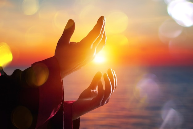 Arab Muslim man hands pray under sunrise light