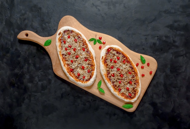 Arab pizza on a wooden stand. Scones with minced meat and pomegranate.