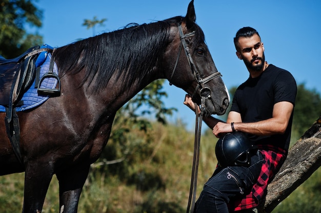 Arab tall beard man wear in black with arabian horse.