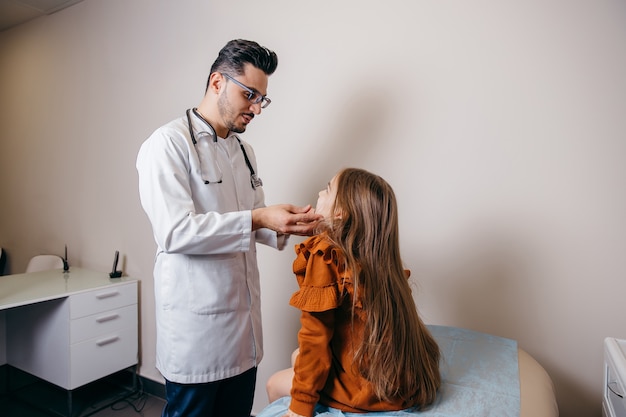 Arab or Turkish pediatrician examining the lymph nodes of a little girl