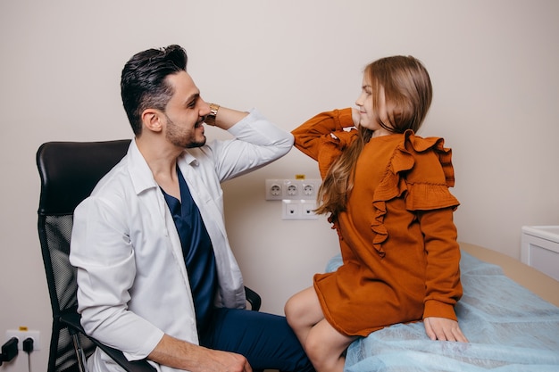 An Arab or Turkish pediatrician greets a little girl with his elbows before being examined