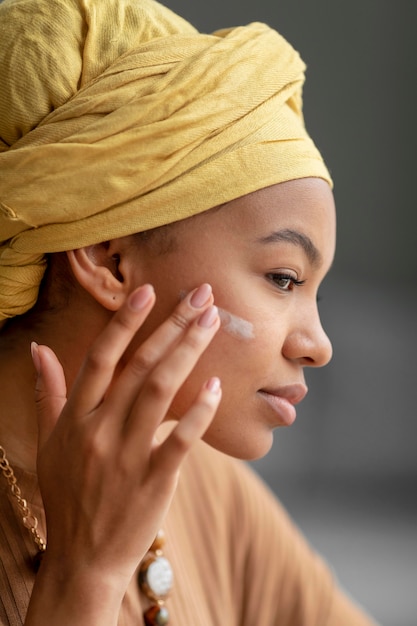 Foto donna araba che applica la crema in faccia. trattamento di bellezza