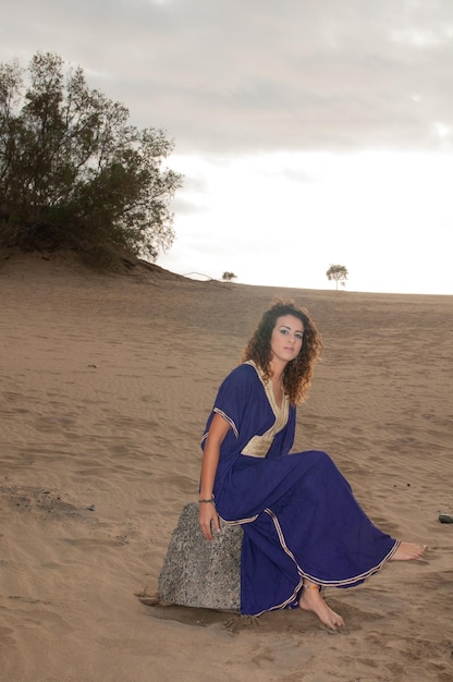 Arab woman in the desert dunes at sunset