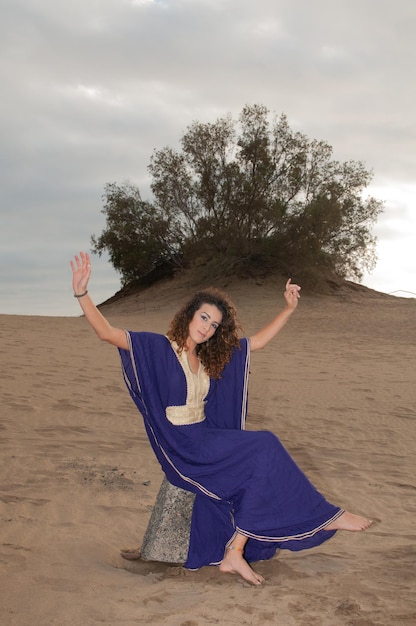 Arab woman in the desert dunes at sunset