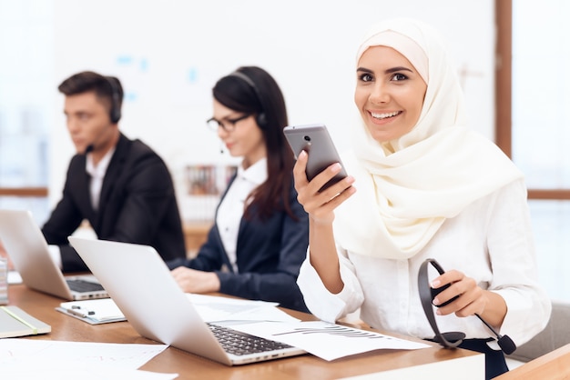 An Arab woman in a hijab looks at the phone.