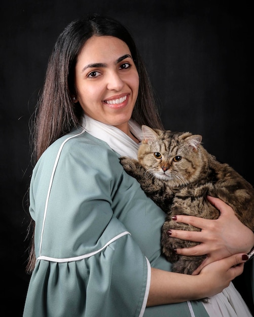 Photo an arab woman holding a cat and smiling