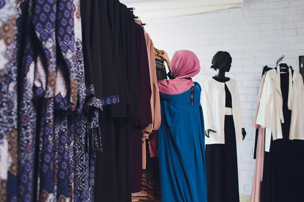 Photo arab woman in traditional muslim clothes buys a new dress in an oriental store