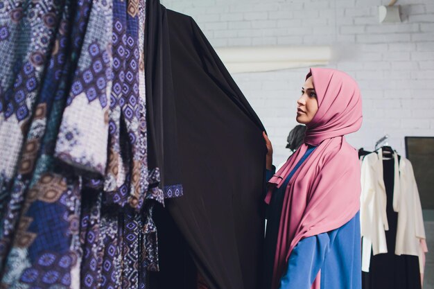 Photo arab woman in traditional muslim clothes buys a new dress in an oriental store