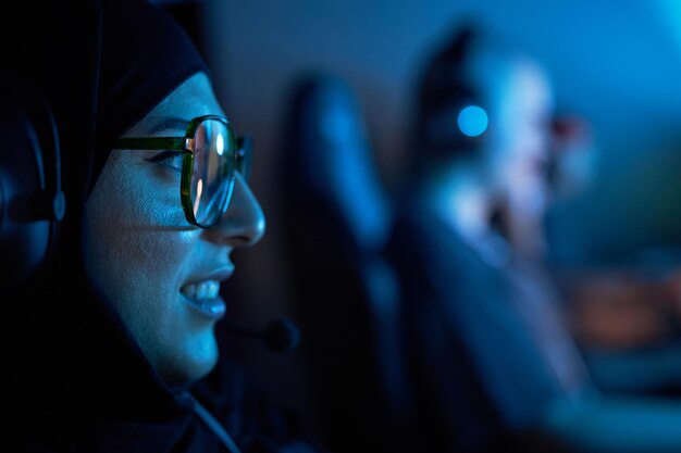 Молодая арабская женщина играет в видеоигры в темноте.