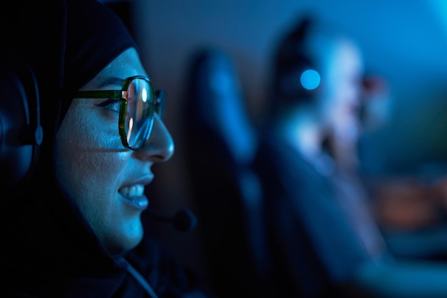 Фото Молодая арабская женщина играет в видеоигры в темноте.