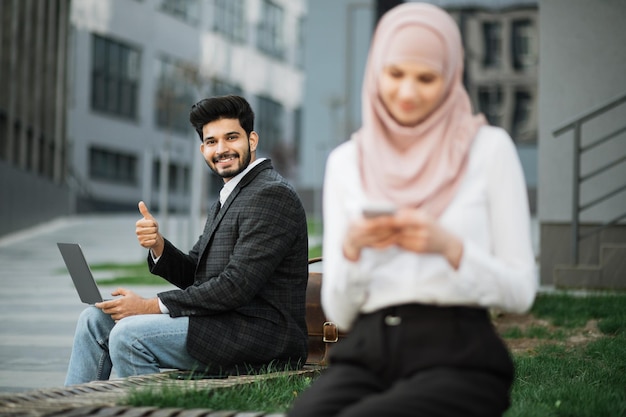 Arabian business people using laptop and cell phone outdoors