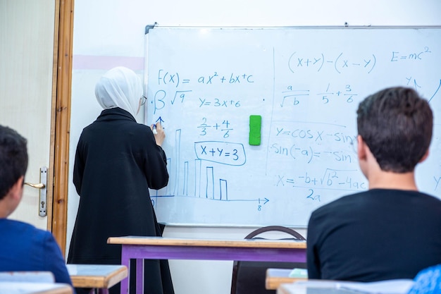 Arabian children\'s in school so excited with their teacher and\
raising their hands to answer the teacher questions