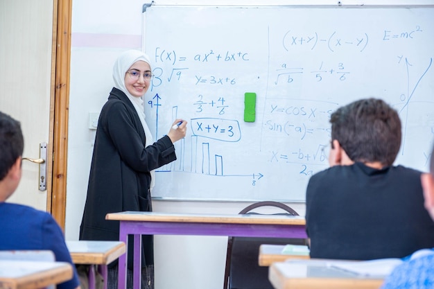 Arabian children\'s in school so excited with their teacher and\
raising their hands to answer the teacher questions