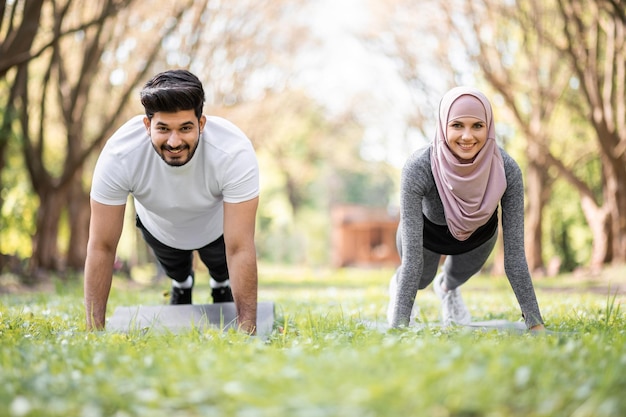 Arabian couple sport clothes doing plank exercise outdoors